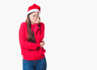 Sticker - Young Chinese woman over isolated background wearing christmas hat looking stressed and nervous with hands on mouth biting nails. Anxiety problem.