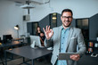 © bnenin - Handsome young businessman showing OK gesture in modern office. Colleagues in the background.