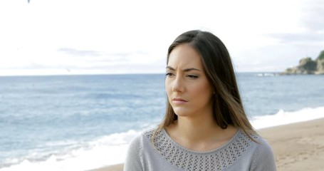 Wall Mural - Melancholic woman walking alone on the beach looking at side