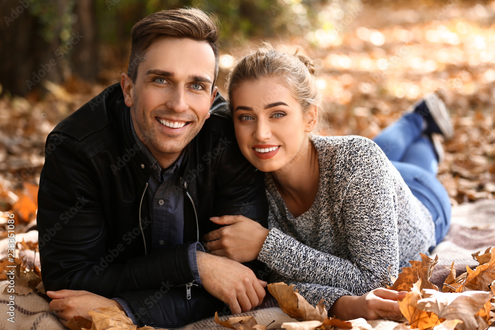 Loving young couple lying on plaid in autumn park