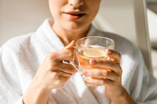 cropped shot of young woman holding cup of herbal drink in spa