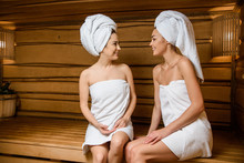 Attractive Young Women Smiling Each Other While Relaxing Together In Sauna