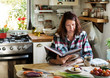 Woman reading a cookbook in the kitchen