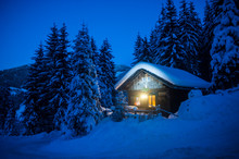 Austria, Altenmarkt-Zauchensee, Sledges, Snowman And Christmas Tree At Illuminated Wooden House In Snow At Night