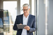 © Westend61 - Businessman standing by window, using digital tablet