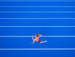 © Westend61 - Overhead view of female runner running on tartan track