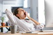 Sleepy young woman dressed in shirt sitting at her workplace