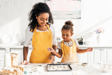 African American Mother And Daughter Looking At Cookies On Tray In Kitchen