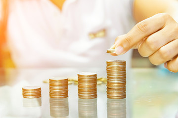 Saving money, save money concept, woman hold stacking coins into increasing columns.