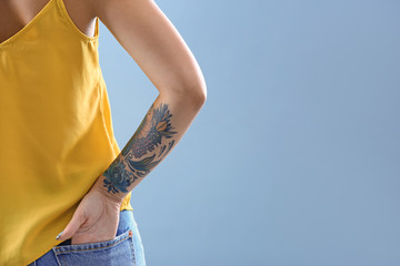 Wall Mural - Young woman with tattoo on color background, closeup. Space for text