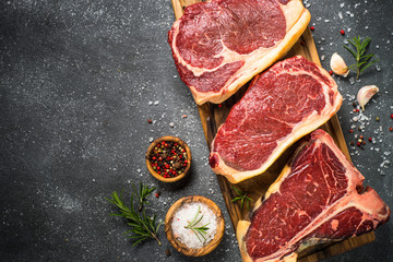 Raw meat beef steak on black top view.