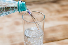 Sparkling Water Is Poured Into A Glass On A Wooden Background.