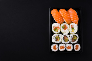 Wall Mural - Japanese food: maki and nigiri sushi set on black background. Flat lay top-down composition. Copyspace