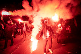 People carry Polish flags and burn flares as they walk across the Poniatowski Bridge during a march marking the 100th anniversary of Polish independence in Warsaw, Poland November 11, 2018. 