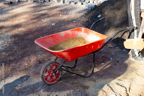 Fotografía Red wheelbarrow with sand on construction site