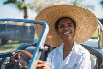 Black woman driving a vintage convertible car