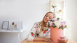 © Ulia Koltyrina - Happy blonde woman in a modern office with flowers in a hat box. Bouquet of peonies.