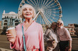 © Yakobchuk Olena - Waist up portrait of stylish adult woman in rose blouse staying on square with her female friends and ferris wheel on background
