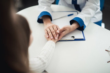 Wall Mural - Concept of positive method of consultation in healthcare system. Close up portrait of pediatrician woman kindly holding hands of female child while consulting