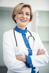 Wall Mural - Concept of professional inspiration in healthcare system. Waist up portrait of smiling female doctor in medical uniform confidently standing in cabinet crossing her arms