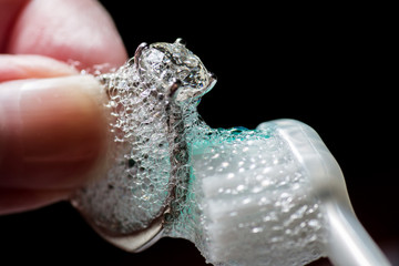 Woman's Hands Cleaning Diamond Ring With Toothbrush and Soap