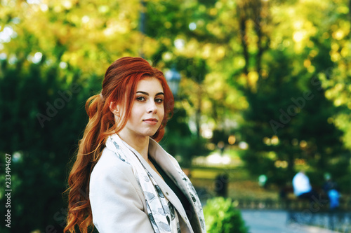 Fényképezés Portrait of a young beautiful fashionable red-haired woman with long curly hair , posing on the streets of the European city