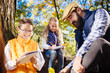 © zinkevych - Our notes. Joyful nice children looking into their notes while being in the forest with their teacher
