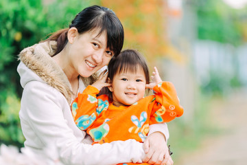 Asian family portrait of 2 years old baby feeling happy and smiles with her mother in the garden. Concept for happiness and healthy people. 