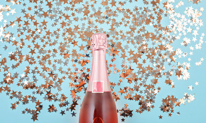 Creative photo of champagne bottle with confetti on blue background