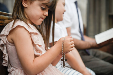 little catholic girl praying with a rosary in her hands