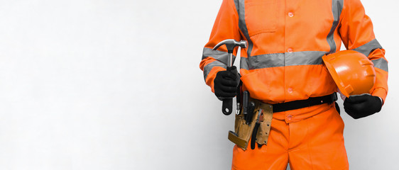 Builder worker is holding in hands a hammer and hard hat isolated on white background. Under construction concept background with copy space.