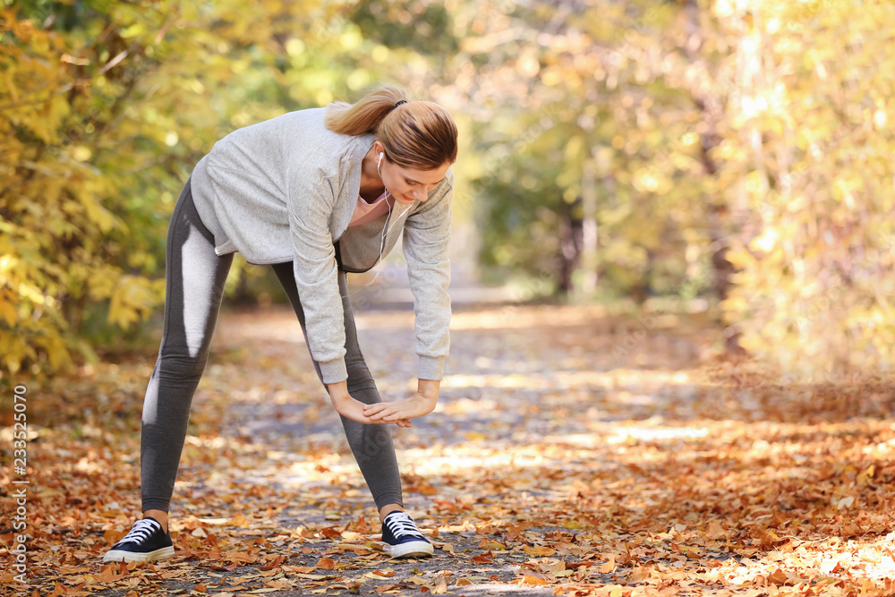 Sporty woman training in park on autumn day