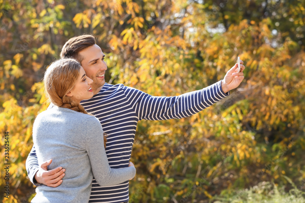 Happy loving couple taking selfie in autumn park