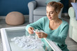 © Pixel-Shot - Woman assembling puzzle on glass table at home