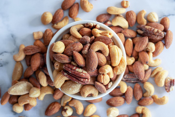 Poster - roasted mixed nuts in white ceramic bowl on barble table background.