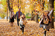 © soleg - Happy family is in autumn city park. Children and parents running with leaves.. They posing, smiling, playing and having fun. Bright yellow trees.