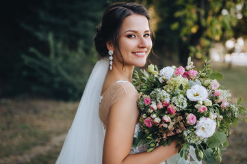 a beautiful bride stands on nature in greenery with a large bouquet. wedding portrait close-up of th