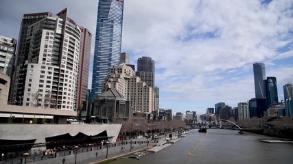 Canvas Print - MELBOURNE - SEPTEMBER 6, 2018: City buildings on a sunny day from Pedestrian Bridge over Yarra River. The city attracts 15 million people annually