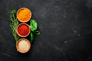 Colored spices on a black stone background. Free space for your text. Top view.