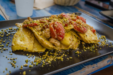 Italian cuisine - pasta - ravioli, served with tomatoes and pistacchio. Beautifully served italian pasta in italian restaurant