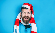Happy Man In Santa Hat Looking Through Hole In Paper. Christmas, New Year, Holidays, Winter Concept. Stylish Guy In Santa Hat&scarf. Smiling Guy In Santa Hat Breaks Through Paper Wall. Christmas Sales