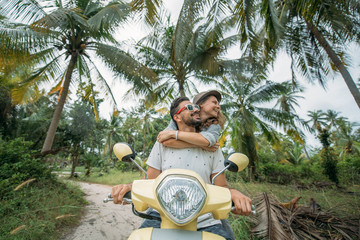 A loving couple travels by scooter through the jungle in Southeast Asia. Smiling and laughing happily