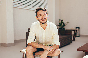 Portrait of happy man sitting outdoors during sunny day