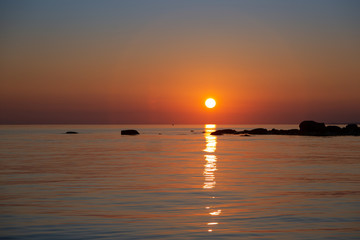 Gold sunset in the ocean with rocks