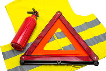 The fire extinguisher and reflective warning triangle lie on the reflective vest, isolated on a white background with a clipping path.