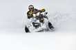 © Tropical studio - In deep snowdrift snowmobile rider make fast turn. Riding with fun in deep snow powder during backcountry tour. Extreme sport adventure, outdoor activity during winter holiday on ski mountain resort.
