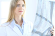 © rogerphoto - Doctor woman osteopathist examining x-ray picture while standing near window in clinic or hospital. Medicine and healthcare concept