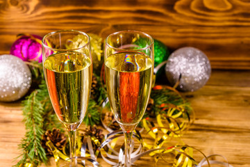 Two wineglasses with champagne and different christmas decorations on wooden table