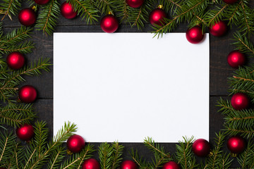 dark rustic wooden table background with white card and christmas decoration - fir and red ornament 