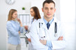 © rogerphoto - Friendly male doctor  on the background with patient  and physician